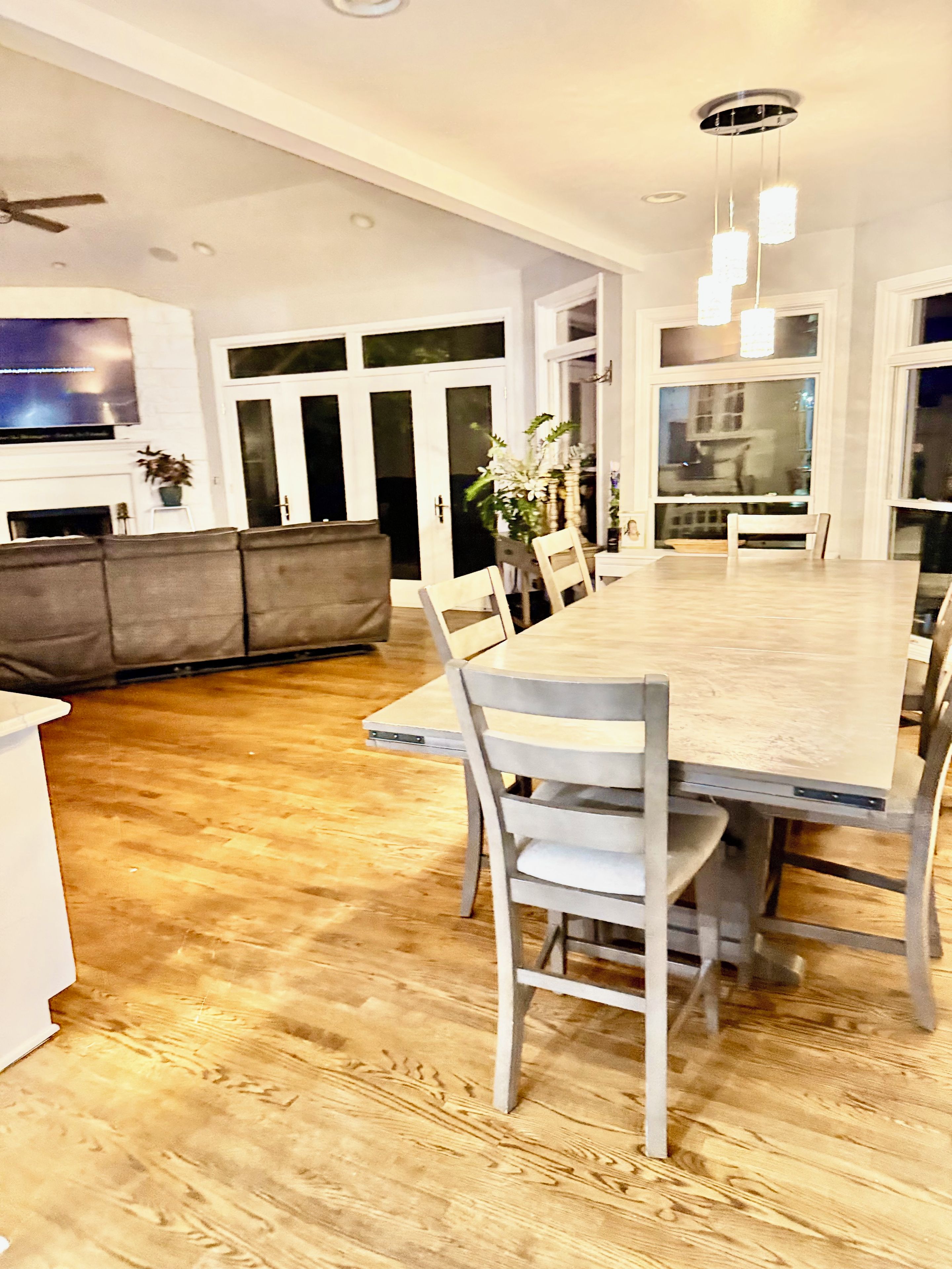 Una cocina moderna con comedor, suelo de madera y una mesa grande con sillas.