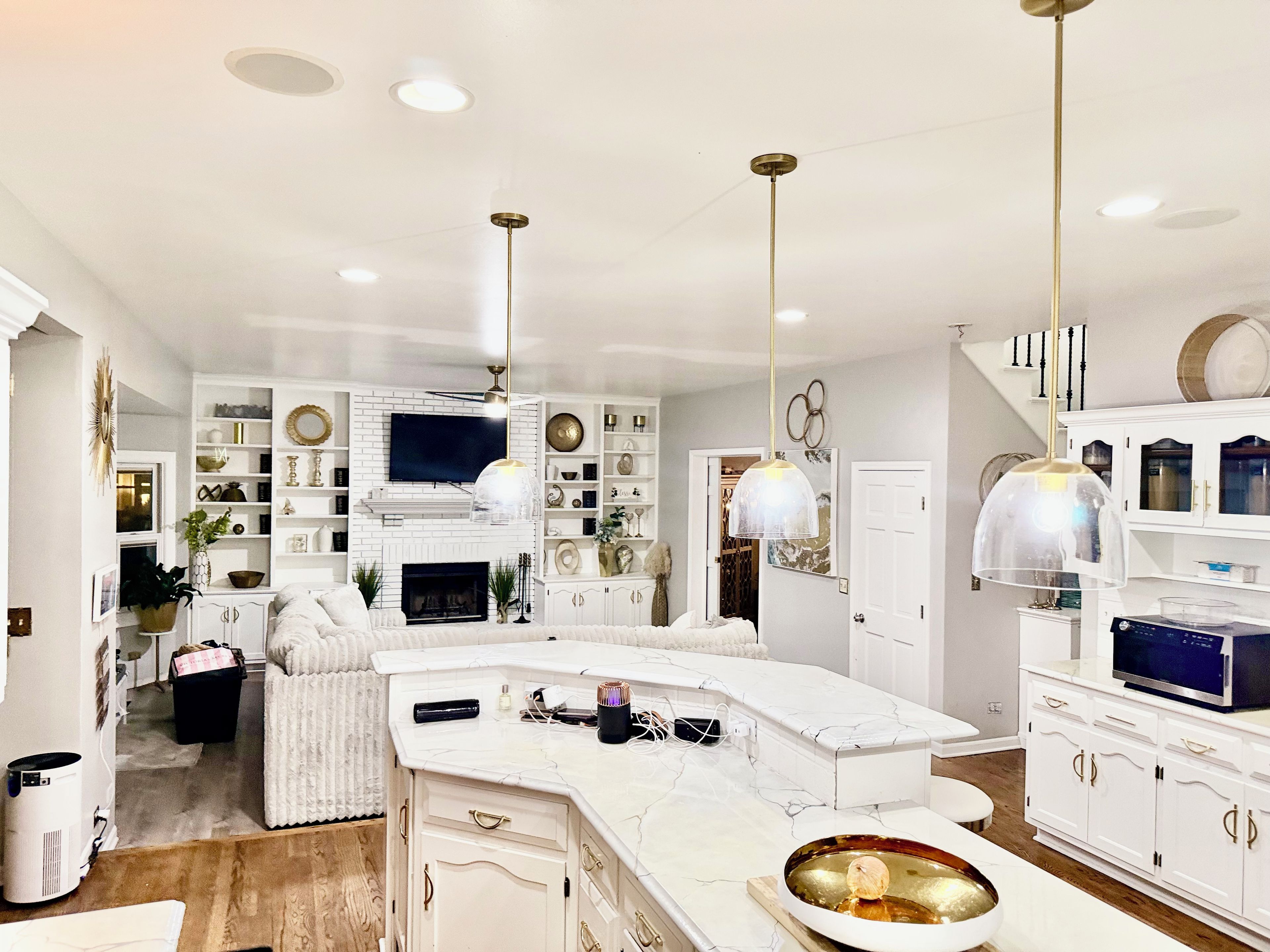 A modern kitchen with a white marble countertop, built-in appliances, and pendant lighting.