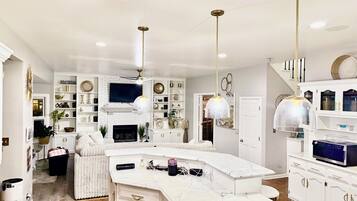 A modern kitchen with a white marble countertop, built-in appliances, and pendant lighting.