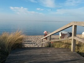 A wooden boardwalk leading to a sandy beach with a clear view of the water.