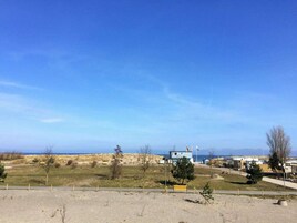 A coastal area with a clear sky, a small building with a flag, and sparse vegetation.