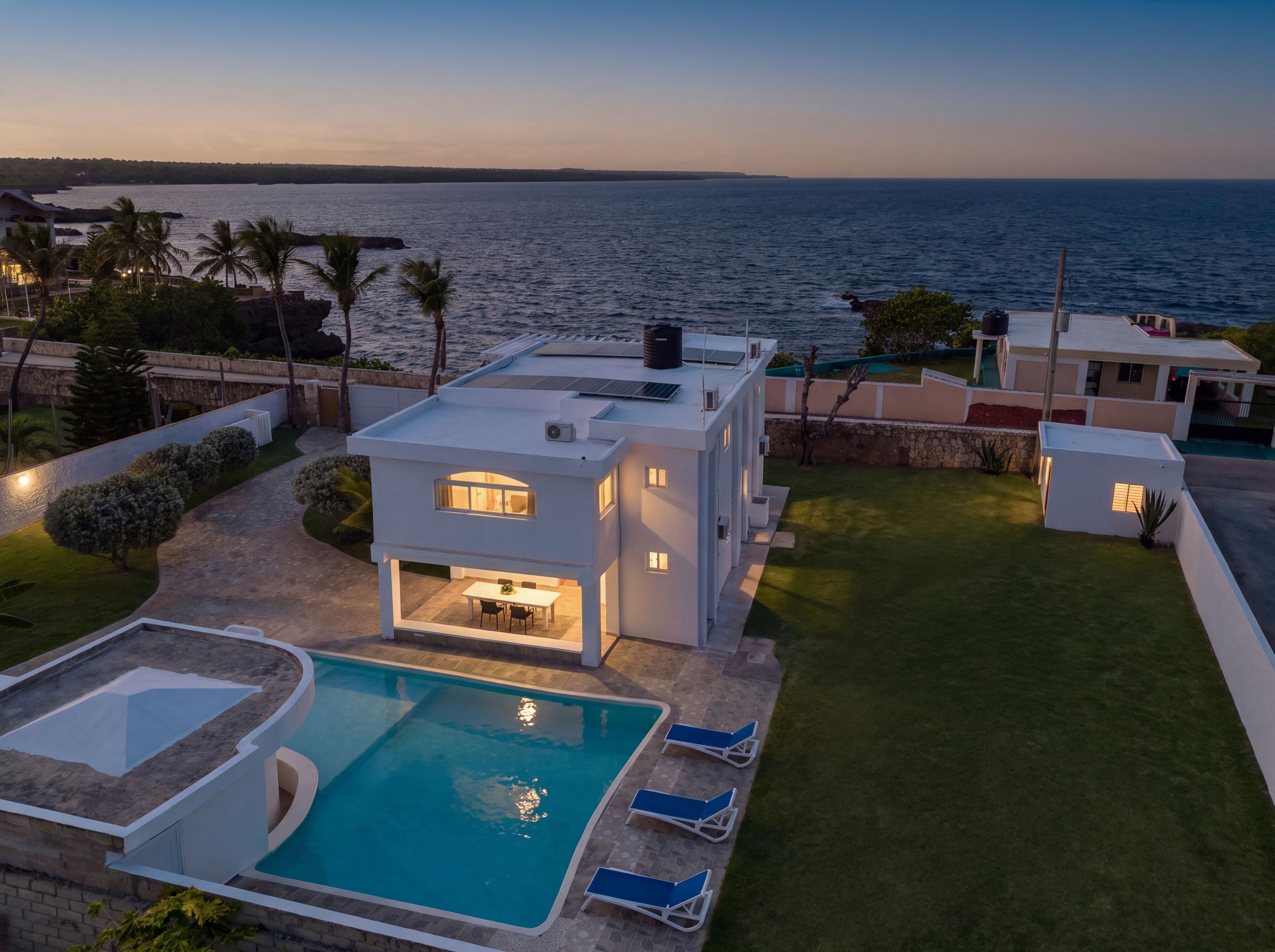 A modern house with a pool, a patio, and a view of the sea.