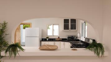 A modern kitchen with white cabinetry, a black countertop, and a central island with a wooden cutting board and a wooden spoon.