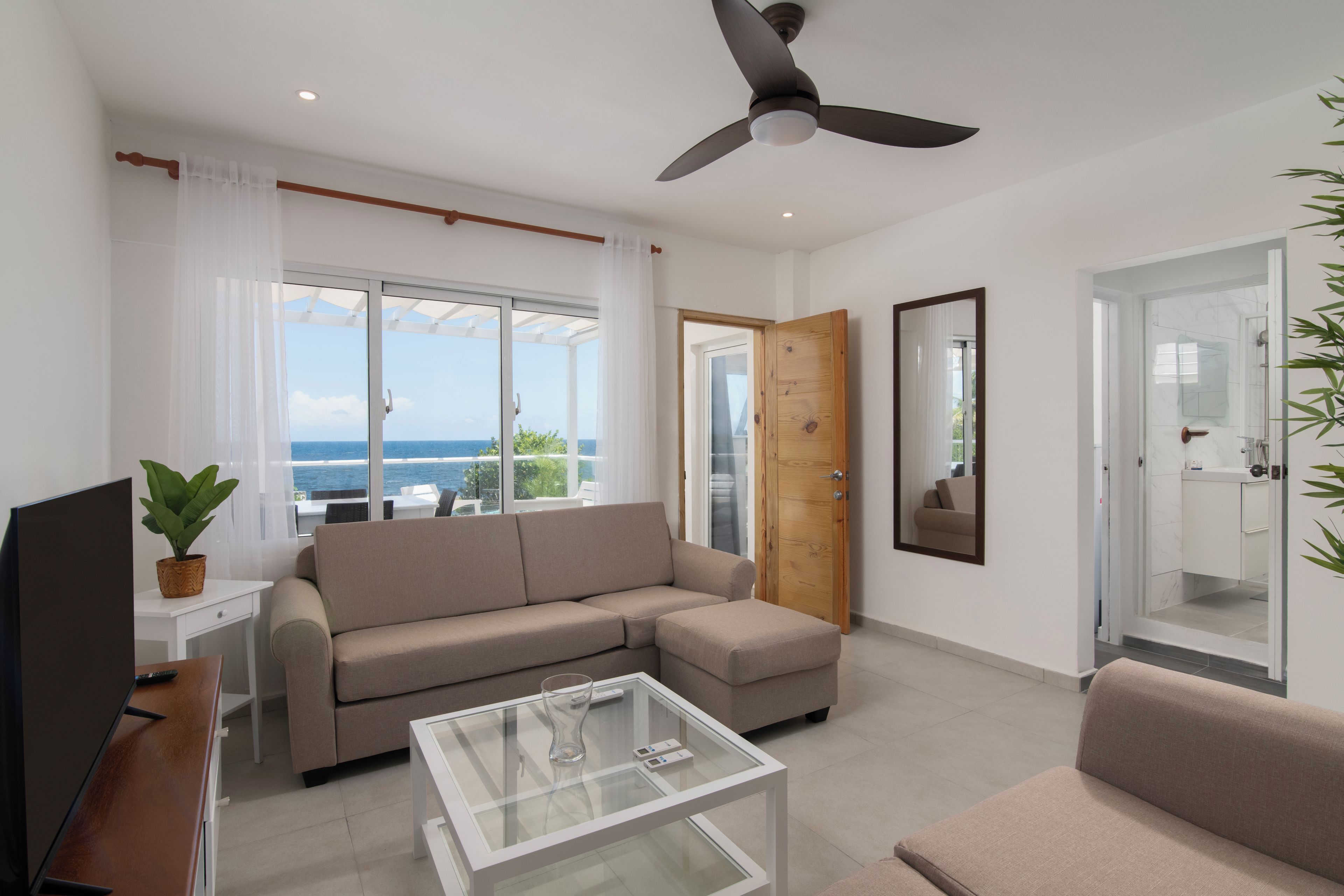 A modern living room with a sofa, a coffee table, a television, and a ceiling fan.