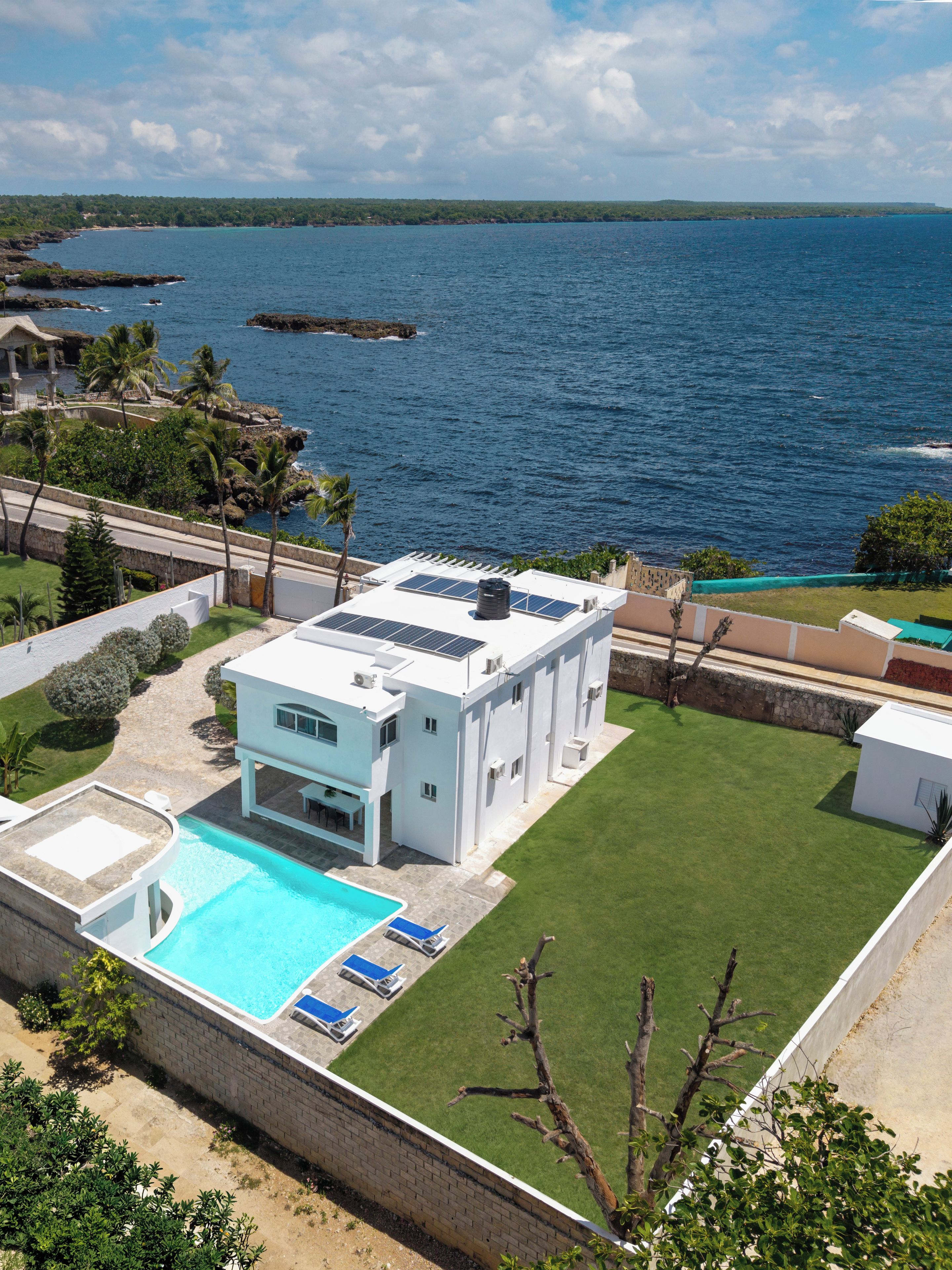 A modern two-story house with a swimming pool, a covered patio, and a view of the ocean.