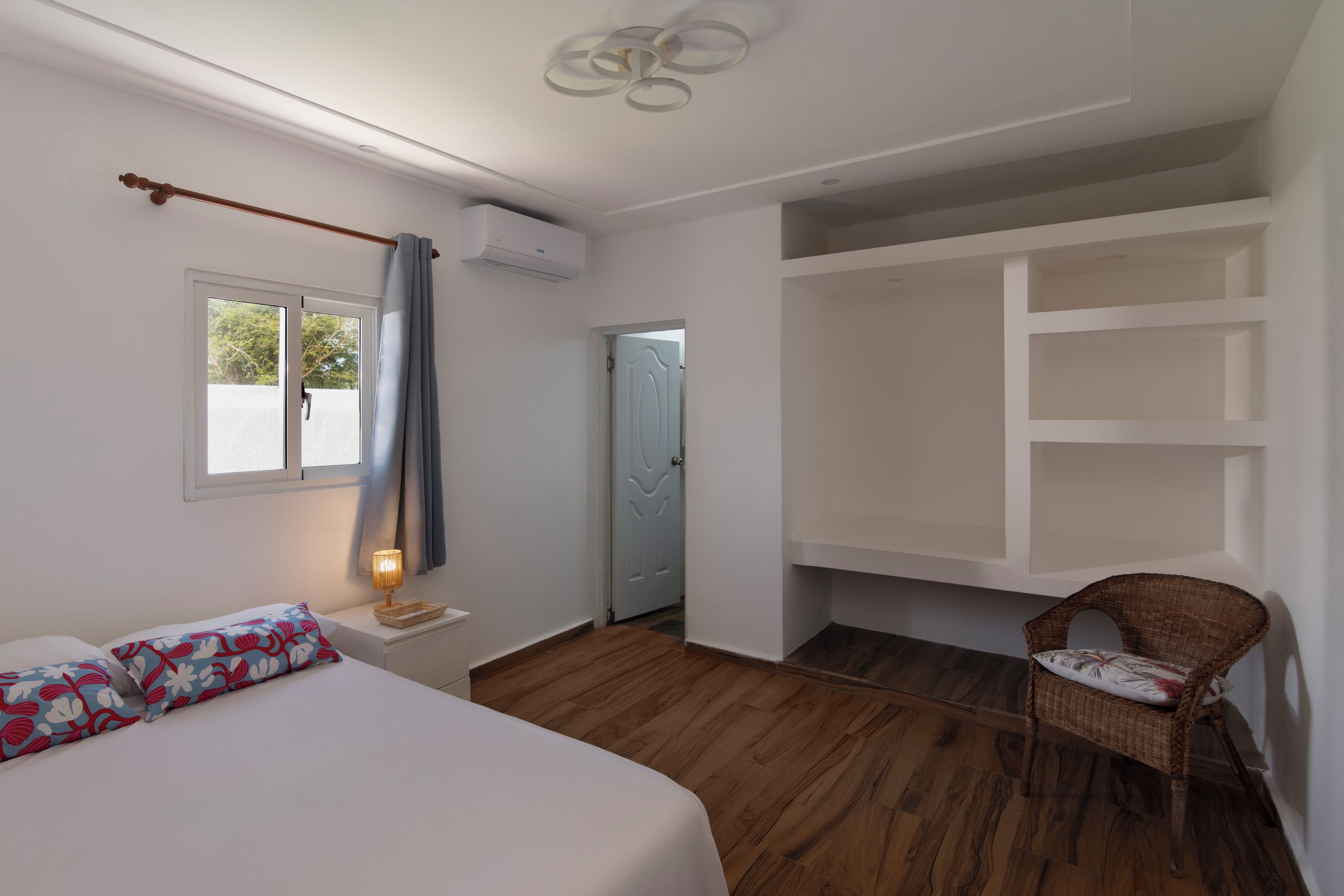 Een slaapkamer met een bed, een stoel, een raam en een deur.