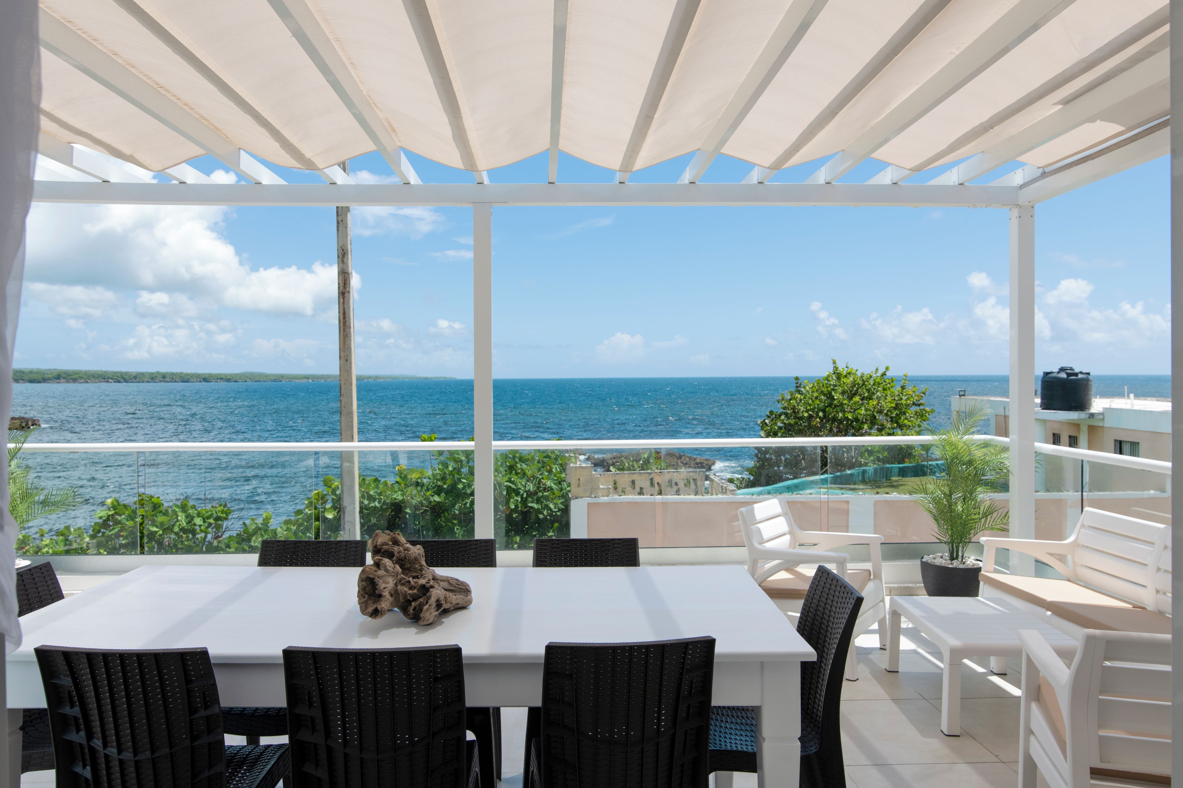 A covered outdoor dining area with a view of the sea.
