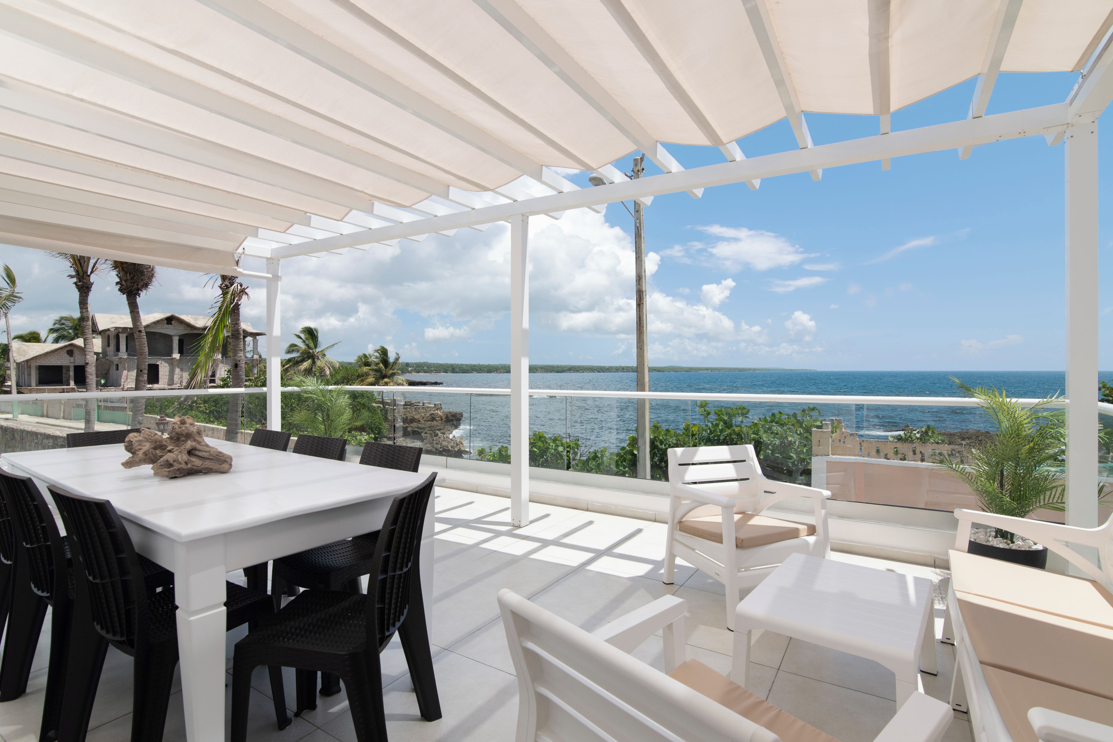 Un espace extérieur abrité, avec une table et des chaises, offrant une vue sur la côte.