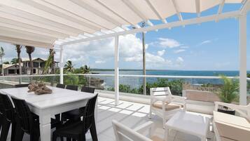 Un espace extérieur abrité, avec une table et des chaises, offrant une vue sur la côte.
