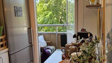 A kitchen with a refrigerator, a coffee maker, and a vase with flowers on the counter.