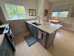 A modern kitchen with a central island, a built-in oven, and a dining area with a table and chairs. - Walkable-Stylish-BRAND NEW! (Raleigh)