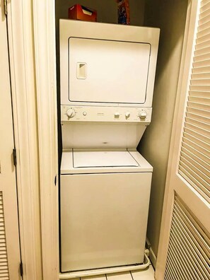 A compact, white, two-door washer and dryer unit in a small laundry room. - Barefoot Resort N. Myrtle Beach: Golf & Beach (North Myrtle Beach)