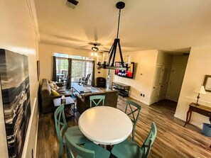 A spacious living area with a dining table, chairs, a sofa, and a television. - Barefoot Resort N. Myrtle Beach: Golf & Beach (North Myrtle Beach)
