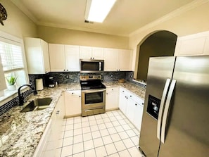 A kitchen with white cabinets, a stainless steel refrigerator, a microwave, and a stove. - Barefoot Resort N. Myrtle Beach: Golf & Beach (North Myrtle Beach)