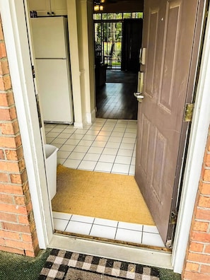 A doorway leading to a tiled interior space with a doormat and a door with a handle. - Barefoot Resort N. Myrtle Beach: Golf & Beach (North Myrtle Beach)