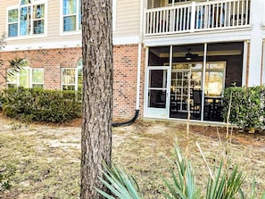 A two-story building with a brick facade, a balcony with a railing, and a sliding glass door leading to an outdoor seating area. - Barefoot Resort N. Myrtle Beach: Golf & Beach (North Myrtle Beach)