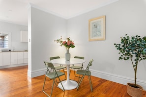 A dining area with a round table, four chairs, a vase with flowers, a framed picture on the wall, and a potted plant. - Light-filled, Cosy Cbd-central Escape Terrace (Sydney)
