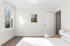 A bedroom with a bed, a door, a window, and a painting on the wall. - Light-filled, Cosy Cbd-central Escape Terrace (Sydney)