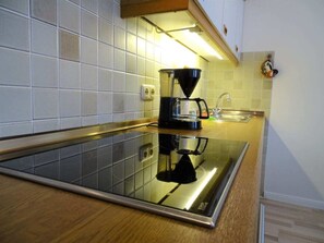 A modern kitchen with a black induction cooktop, a coffee maker, and a stainless steel sink. - Beach House Villa 9 (Dahme)