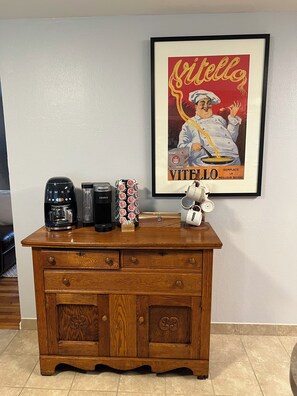 A wooden cabinet with a coffee maker, a sugar container, and a mug on top.