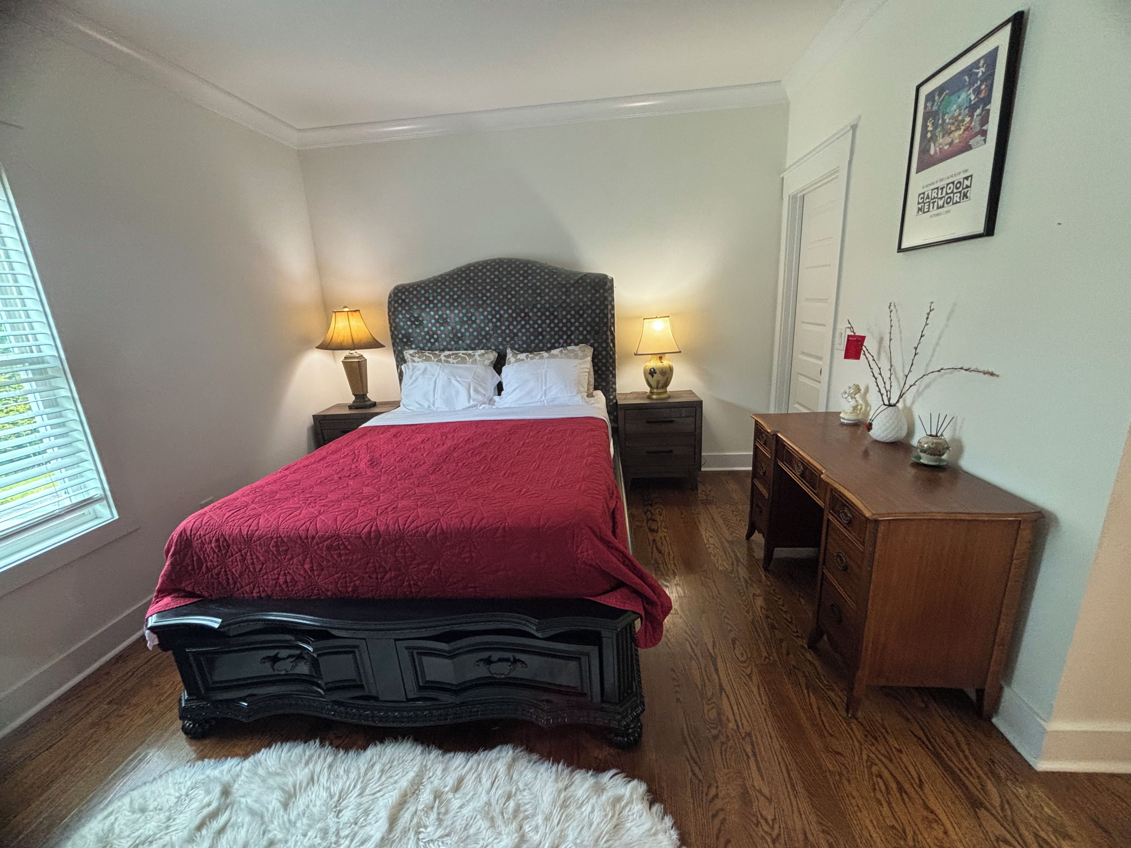 A bedroom with a bed, bedside lamps, a nightstand, a dresser, and a framed picture on the wall.