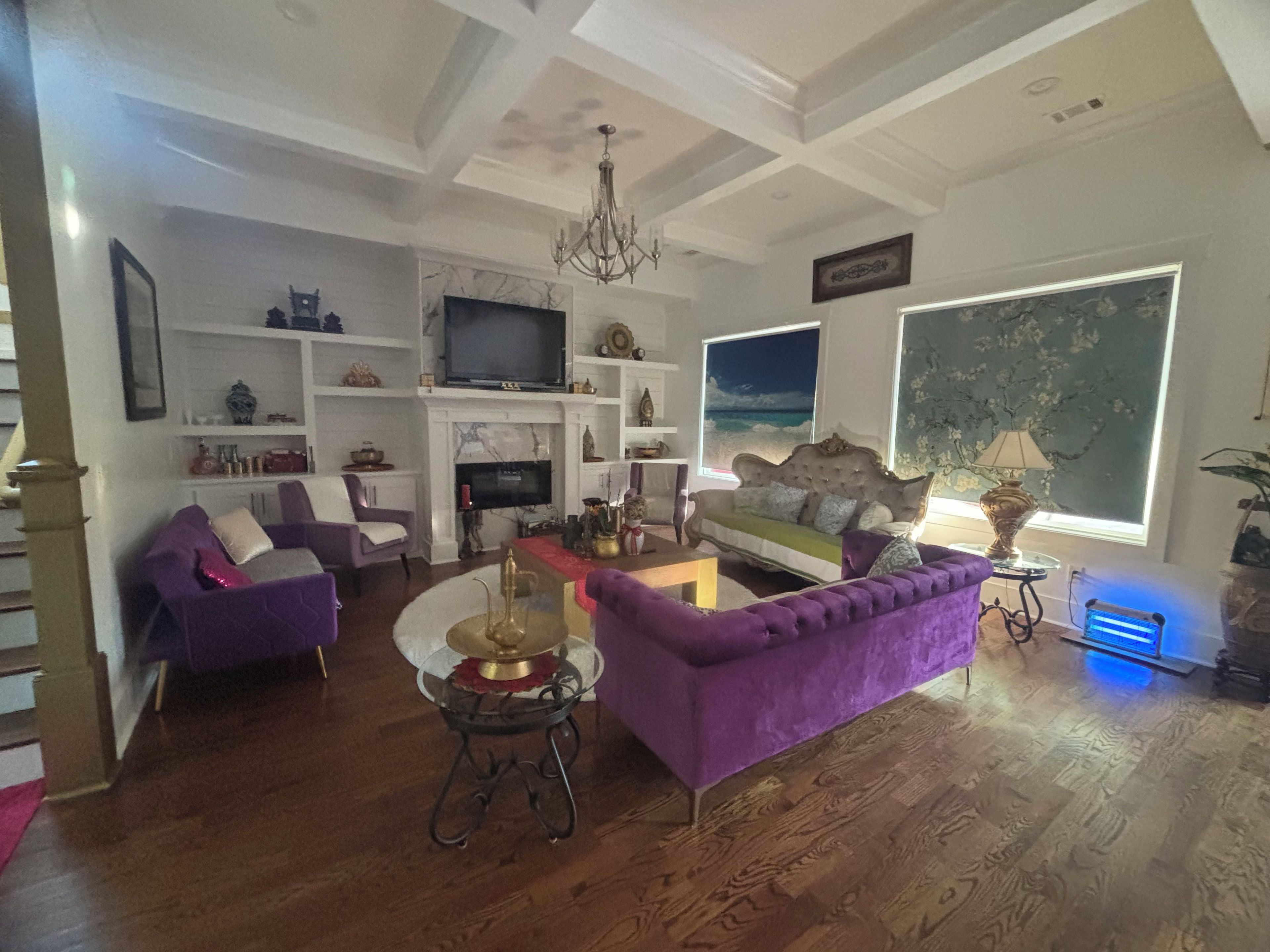 A living room with a fireplace, a television, and a large window with a view.
