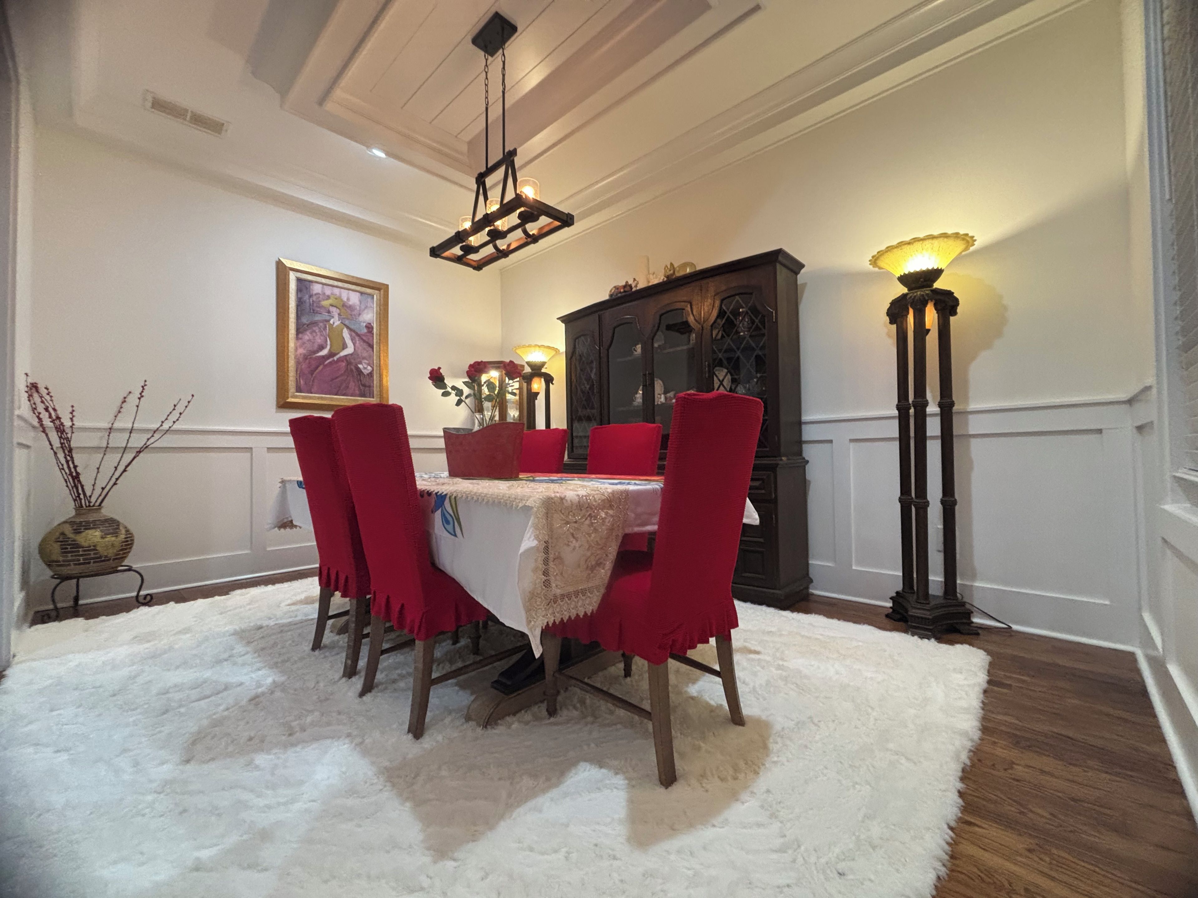 A dining area with a table, chairs, a chandelier, and a cabinet.