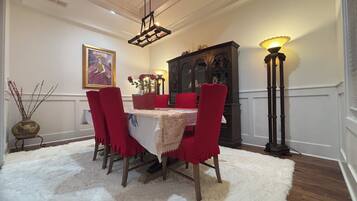 A dining area with a table, chairs, a chandelier, and a cabinet.