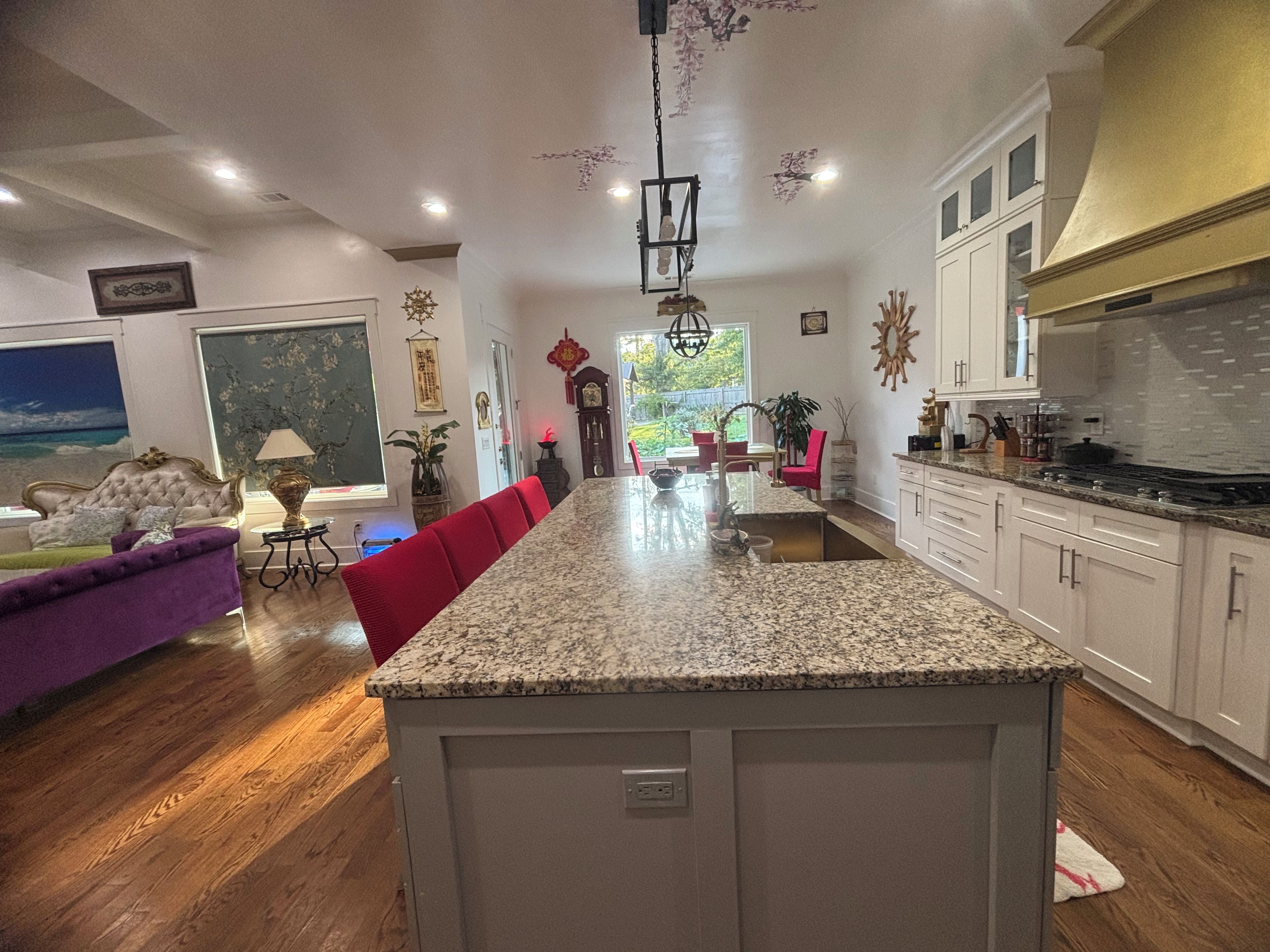 A spacious kitchen with granite countertops, white cabinetry, and a large island.