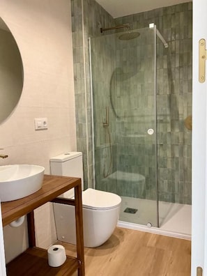 Ein Badezimmer mit einer Duschkabine, einem Holzkosmetikschrank mit Waschbecken und einer Toilette.