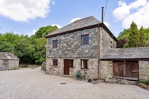 A stone building with a gravel driveway and a small garden area with a bench. - 1-bedroom Cornish Hideaway (Bodmin)