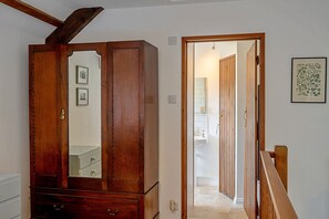 A hallway with a wooden wardrobe, a mirror, and a framed botanical print on the wall. - 1-bedroom Cornish Hideaway (Bodmin)