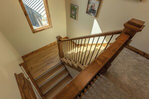 A wooden staircase with a handrail and a carpeted landing. - Teton Homestead: Main House at Restoration Ranch (Tetonia)