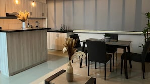 Cozinha moderna com ilha central, área de jantar com cadeiras e iluminação pendente.