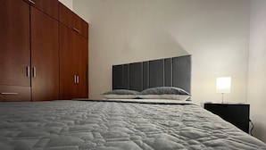 Quarto com uma cama grande, um guarda-roupa e uma mesa de cabeceira com abajur.