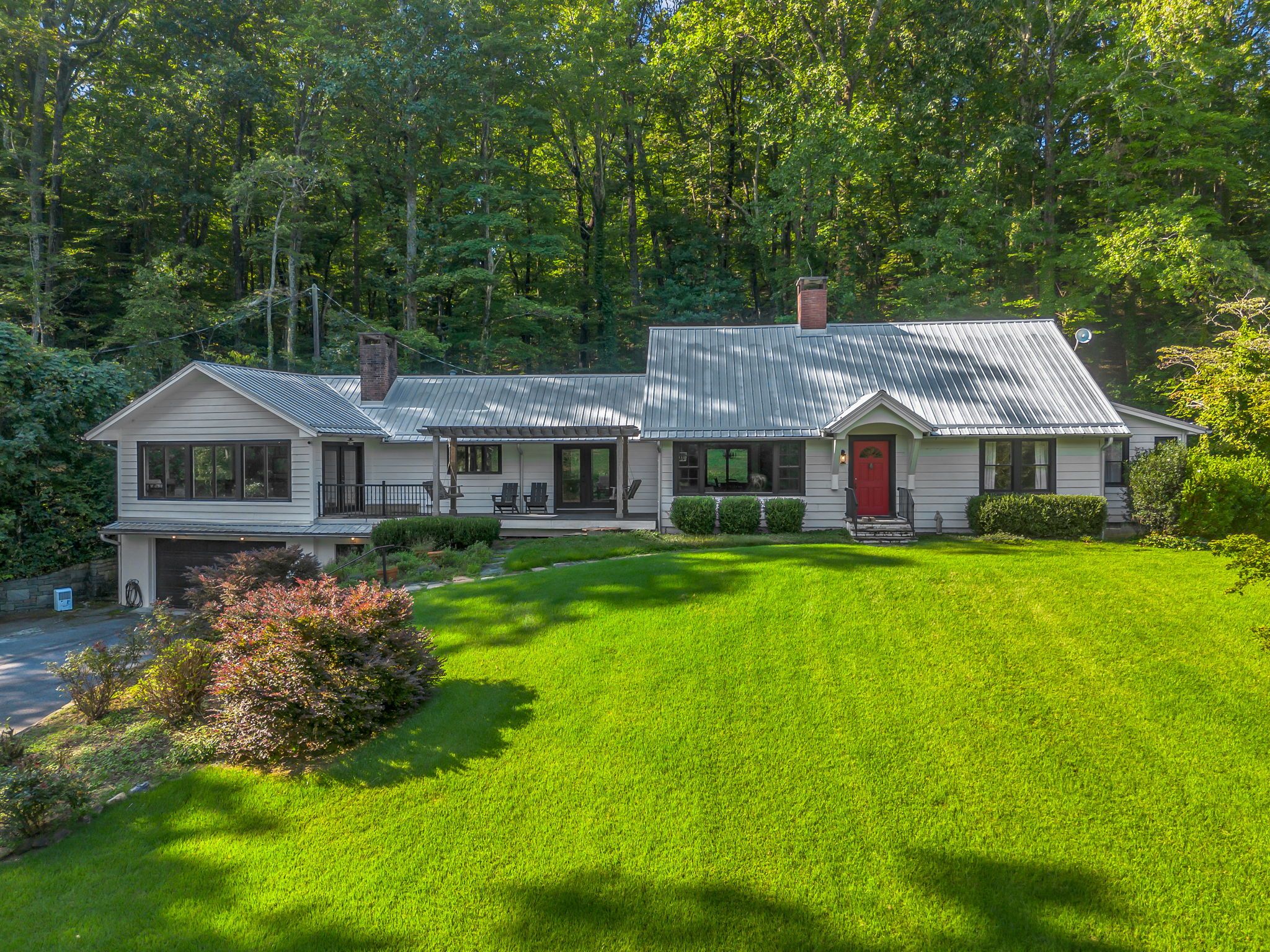 A two-story house with a garage, a red door, and a well-maintained lawn.