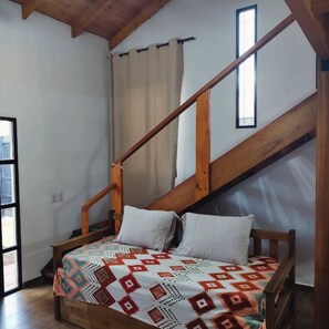 A bedroom with a wooden bed, a sloped ceiling, and a window. - Alojamiento Iguazú Yvyra  (Puerto Iguazú)