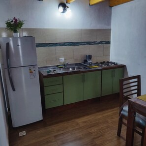 A compact kitchen with a refrigerator, sink, stove, and cabinets. - Alojamiento Iguazú Yvyra  (Puerto Iguazú)