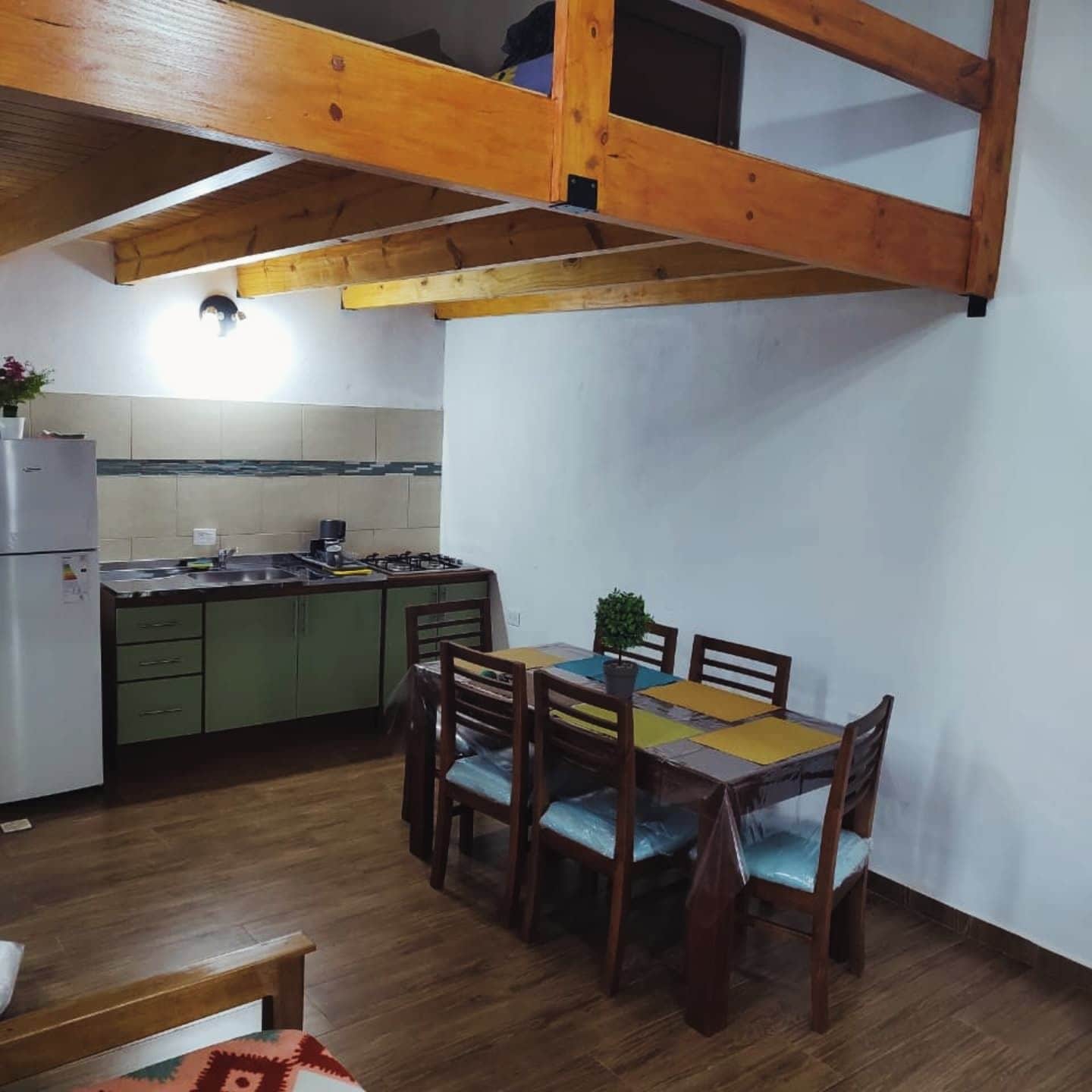 A compact kitchen with a dining area, wooden ceiling beams, and a small table with chairs.