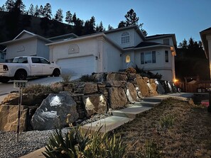 Una propiedad residencial con garaje, entrada para vehículos y zona ajardinada con rocas y plantas.