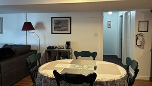 En matplats med ett runt bord, stolar, en lampa och en kaffemaskin.
