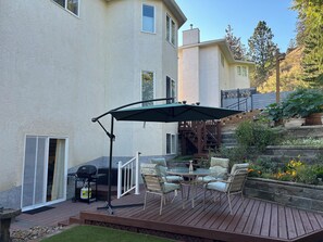 Una terraza con mobiliario exterior, una parrilla y un área cubierta.