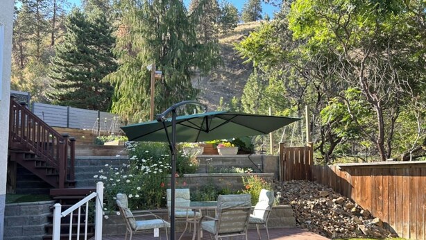 En uteplats med utemöbler, en pergola och en stenmur.