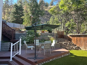 A deck with outdoor furniture, a pergola, and a stone wall.