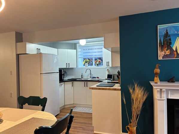 A modern kitchen with white cabinets, a dining area with a table and chairs, and a fireplace.