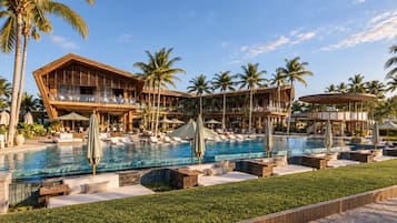 Resort com uma piscina grande, várias áreas de estar e um edifício de vários andares com varandas.