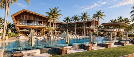 A resort with a large pool, multiple lounge areas, and a multi-story building with balconies.