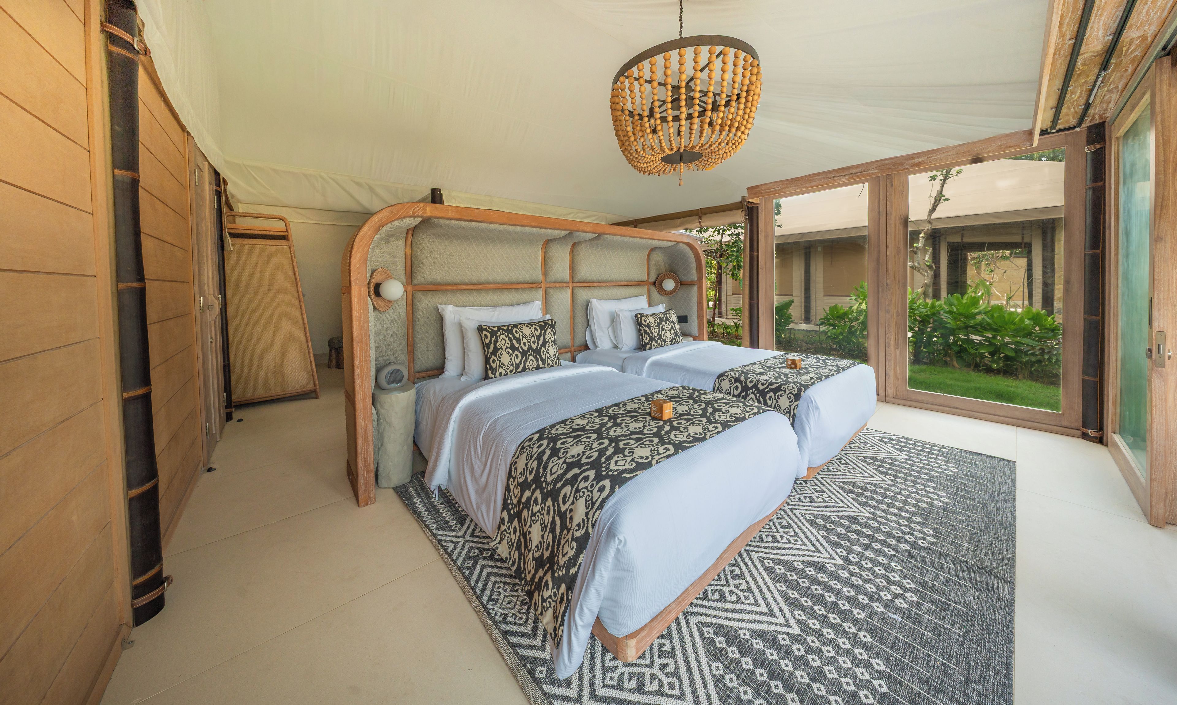 Une chambre spacieuse avec un grand lit, un luminaire suspendu et une vue sur l’extérieur.