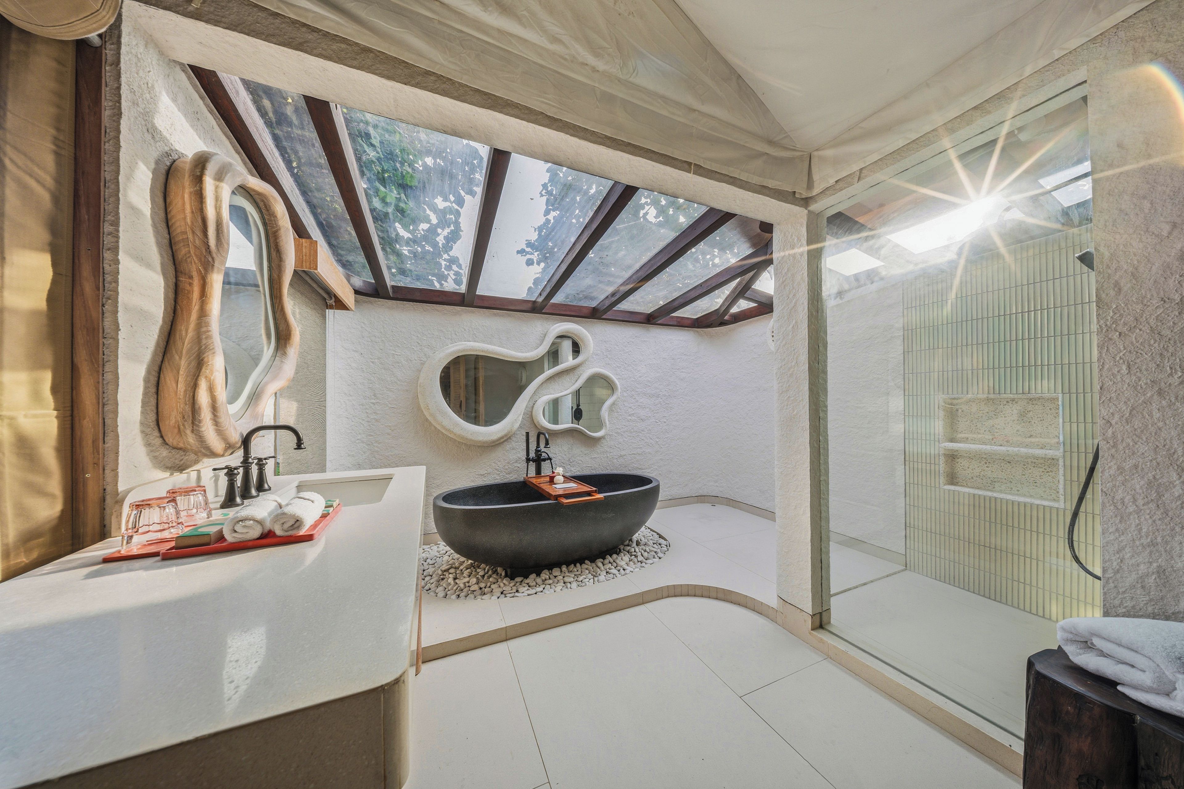 A modern bathroom with a freestanding bathtub, a large mirror, and a skylight.