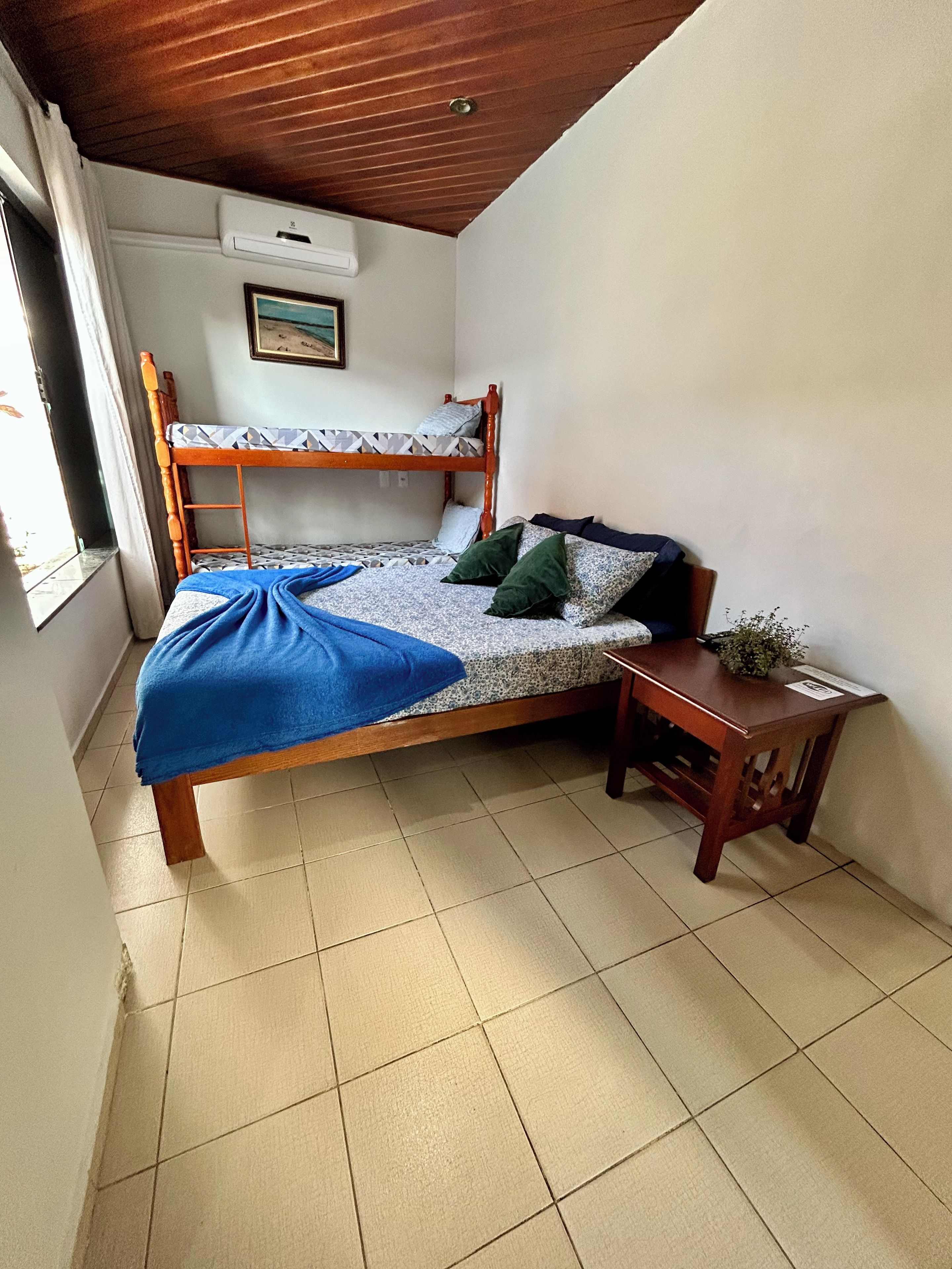 A room with a bunk bed, a small wooden table, and a window with curtains.